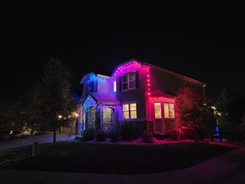 Corner-lot home with a blue to pink gradient of permanent eave lights