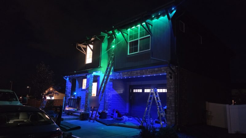Two-story home with green and blue permanent eave lighting at night
