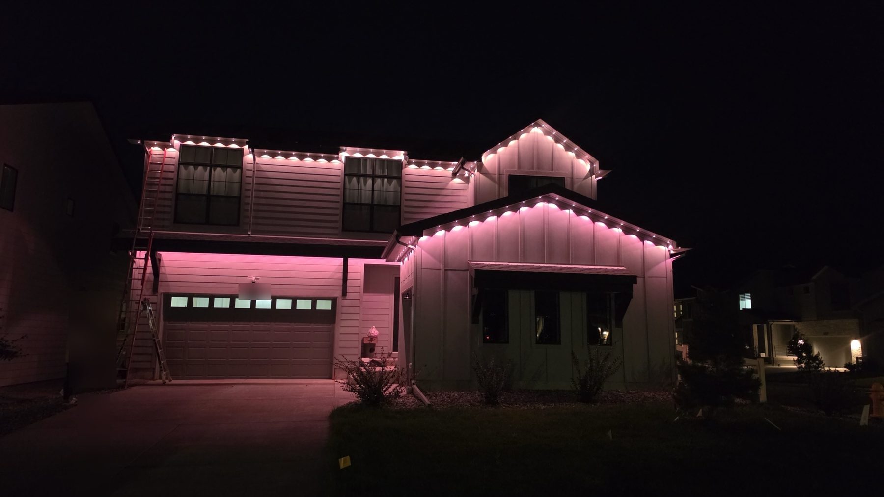 Home at night with a soft pink wash of permanent eave lighting
